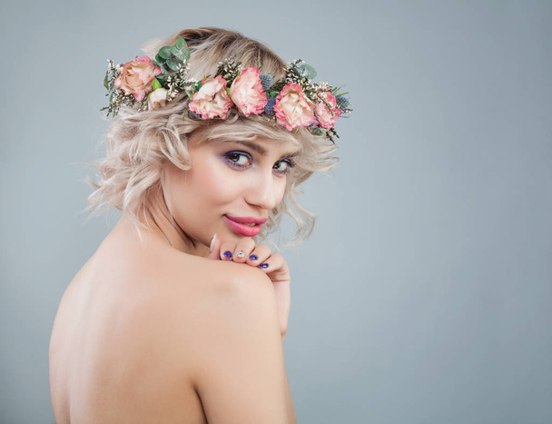 Mujer agradable con piel sana, maquillaje, flores y pelo rizado corto
 - Foto, Imagen