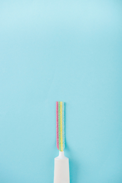 vista superior del tubo de pasta de dientes con masticar caramelos de colores aislados en azul con espacio de copia
 - Foto, Imagen