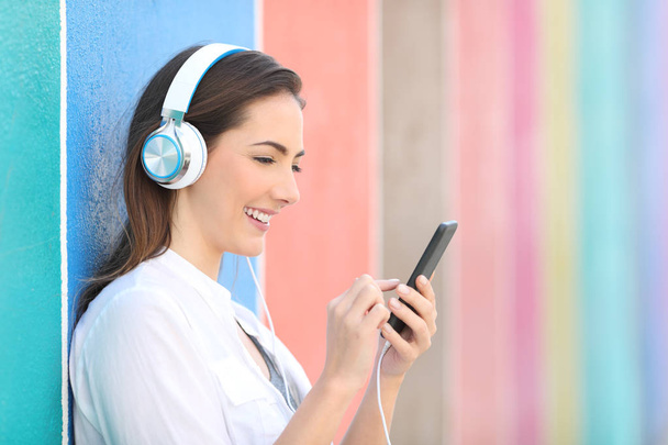 Happy girl listening to music checking songs on phone - Foto, Imagem