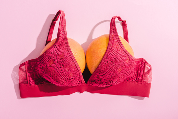 верхний вид лифчика с двумя апельсинами на розовый, концепция груди
 - Фото, изображение