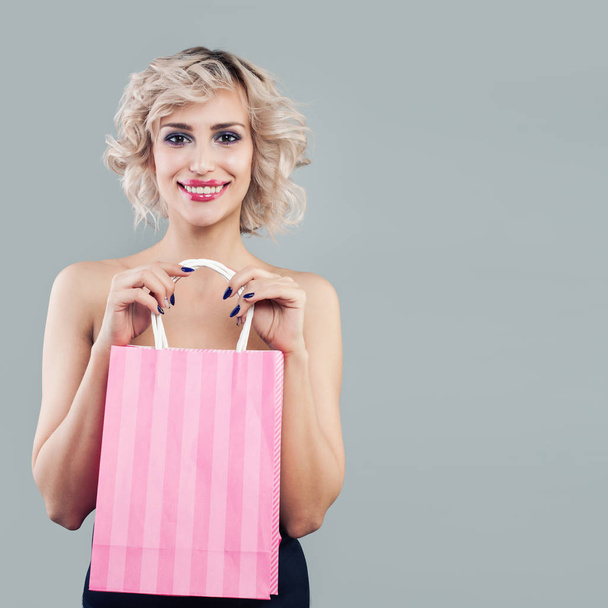Happy Blonde kobieta trzyma różowe torby na zakupy i uśmiechnięty - Zdjęcie, obraz