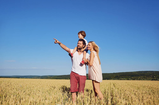 A happy family standing in a wheat field. - Foto, Imagen