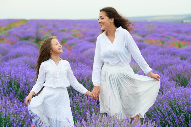 girls are in the lavender flower field, beautiful summer landscape - Fotografie, Obrázek