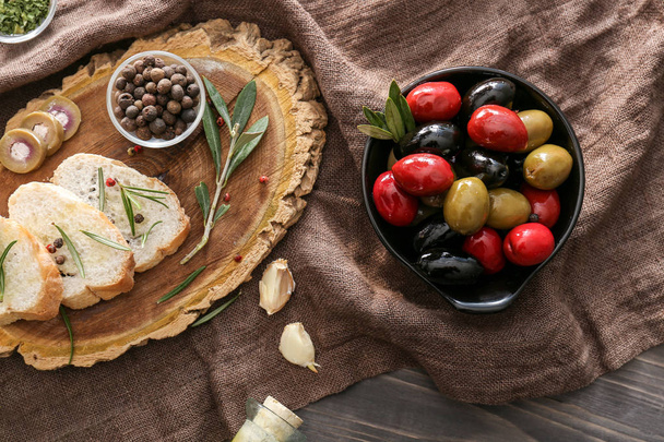 Вкусные оливки с хлебом и специями на столе
 - Фото, изображение