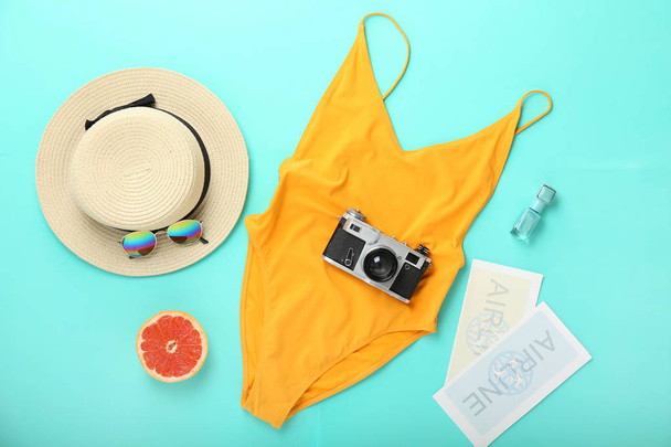 Vrouwelijk badpak met accessoires, fotocamera en kaartjes op kleur achtergrond - Foto, afbeelding
