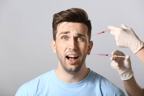 Ijedt férfi és kezében fecskendők az anti-aging injekciót világos háttér - Fotó, kép