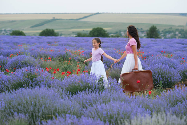 young woman and girl are walking through the lavender flower field, beautiful summer landscape - Φωτογραφία, εικόνα