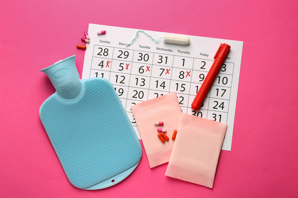 Menstrual calendar with feminine products, water bag and pills on color background - Photo, Image
