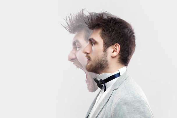 profile portrait of two-faced young man in calm serious and angry screaming expressions on grey background. concept of different emotion inside and outside mood of people  - Фото, зображення