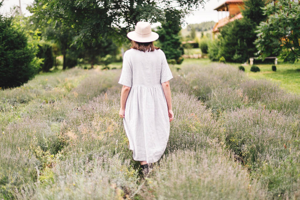 Élégante fille hipster en robe de lin et chapeau marchant dans la lavande
  - Photo, image