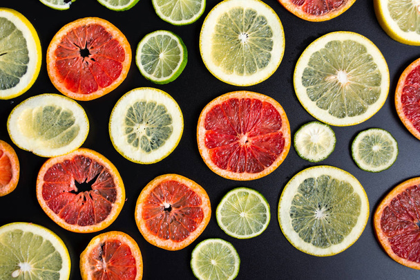 Sliced citrus fruits on a dark background pattern - Фото, зображення