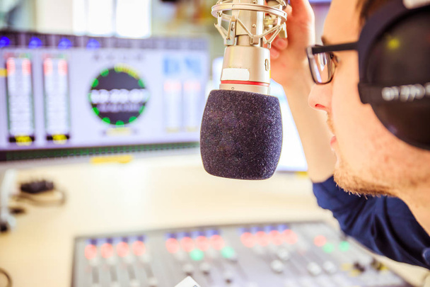 Radio moderator is sitting in a modern broadcasting studio and t - 写真・画像