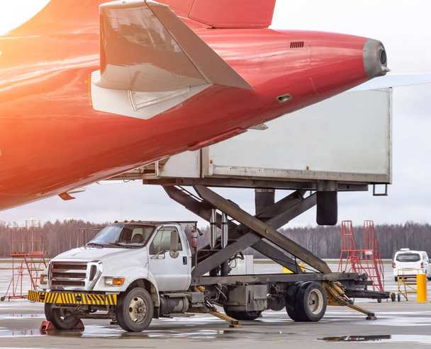 Loading platform truck of air freight to the tail aircraft. Food for flight check-in services and equipment to ready before boarding the airplane. - Photo, Image