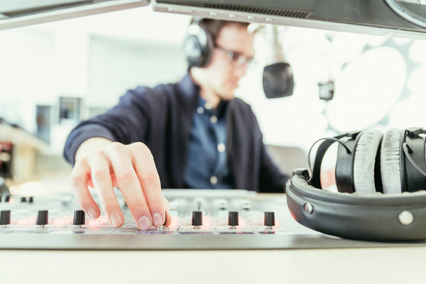 Radio moderator is sitting in a modern broadcasting studio and t - Zdjęcie, obraz