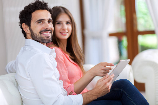 No casal de amor usando um computador tablet em sua sala de estar
 - Foto, Imagem