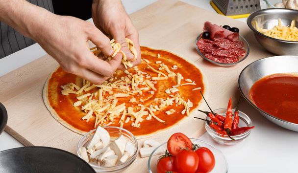Italian dish. Chef adding grated cheese to pizza - Foto, Imagen
