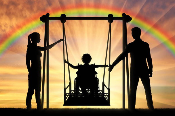 Sylwetka szczęśliwego dziecka jest osobą niepełnosprawną na wózku inwalidzkim na adaptacyjnym huśtawce - Zdjęcie, obraz