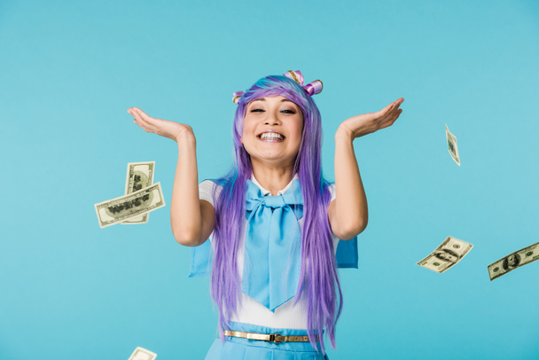 Excited asian anime girl with dollar banknotes isolated on blue - Photo, image