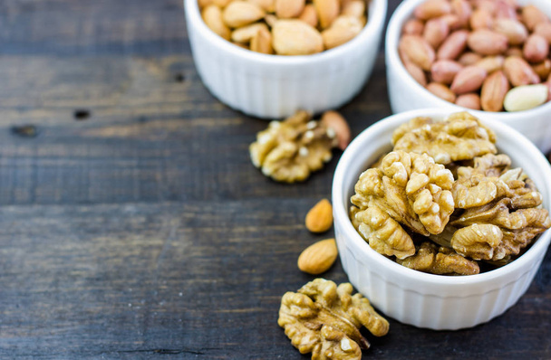 Tasty nuts arrangement in a bowl on a wooden table. Healthy food and snack, organic vegetarian food. Walnut, almond, peanut - Foto, Bild