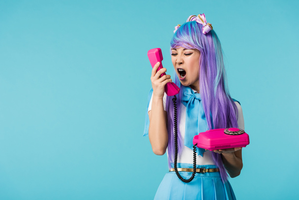 Angry asian anime girl screaming in handset isolated on blue - Foto, Imagem