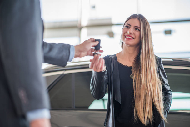 Woman taking the keys for her car in a showroom - Φωτογραφία, εικόνα