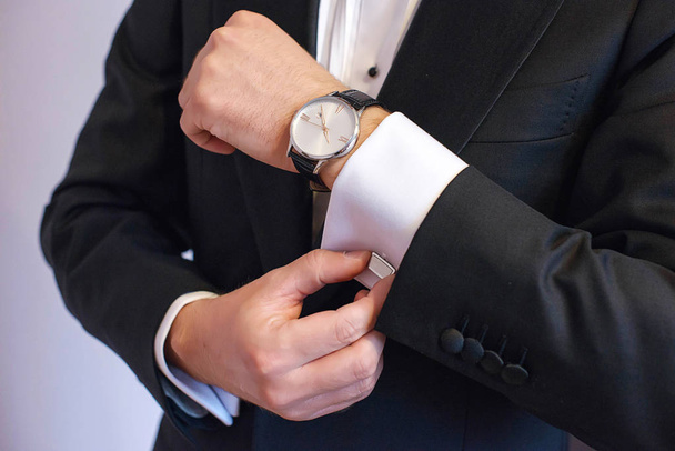Close-up shot of young white Caucasian male in black tie, fixing his cuff links sign of sprezzatura and elegance. Groom, or sophisticated businessman, or millennial male model getting ready. - Zdjęcie, obraz
