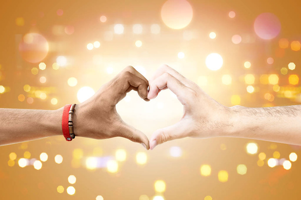 Ζευγάρι των γκέι κάνοντας ένα σύμβολο της καρδιάς με το χέρι με θολά φώτα φόντο. ΛΟΑΤ έννοια - Φωτογραφία, εικόνα