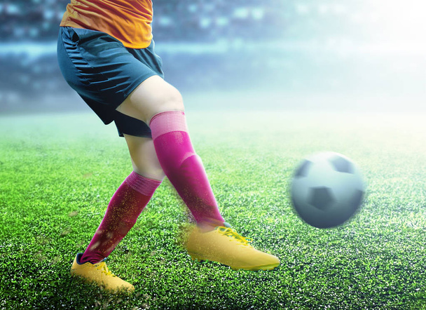 フットボールのジャージでサッカー選手の女性はサッカー場でボールを蹴る  - 写真・画像