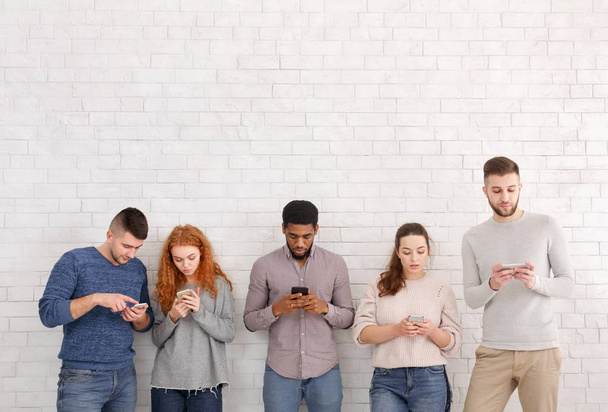 Internetsucht. Schüler mit Smartphones über weiße Wand - Foto, Bild