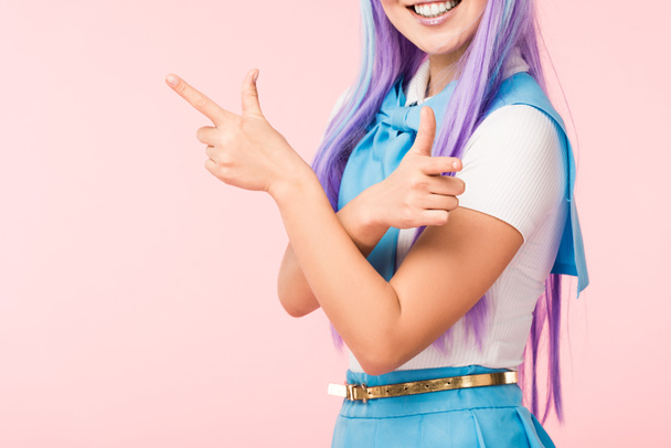 Vista cortada de anime alegre menina em peruca roxa apontando com os dedos isolados em rosa
 - Foto, Imagem