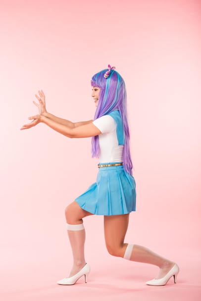 Full length view of smiling otaku girl in purple wig posing on pink - Фото, зображення