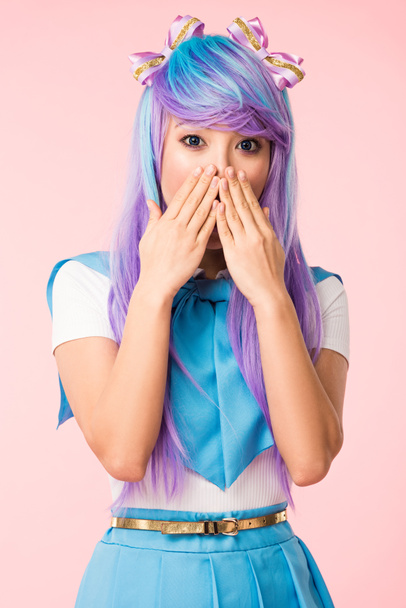 Шокована азіатська аніме дівчина в перуці покриває рот руками ізольовано на рожевому
 - Фото, зображення