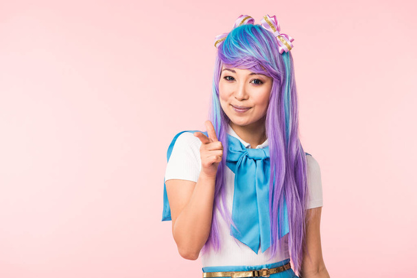 Usmívající se asijský anime dívka s prstem izolovaným na růžovém - Fotografie, Obrázek