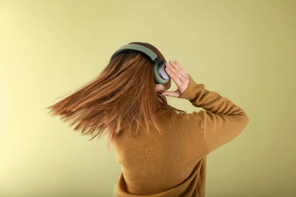 Young woman with headphones listening to music on color background - Foto, afbeelding