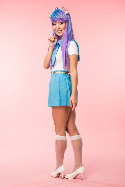 Full length view of otaku girl in purple wig smiling on pink - Foto, afbeelding