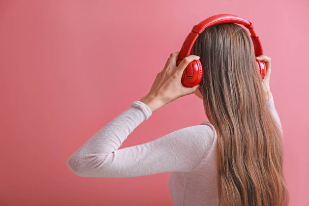 Junge Frau mit Kopfhörern hört Musik auf farbigem Hintergrund - Foto, Bild