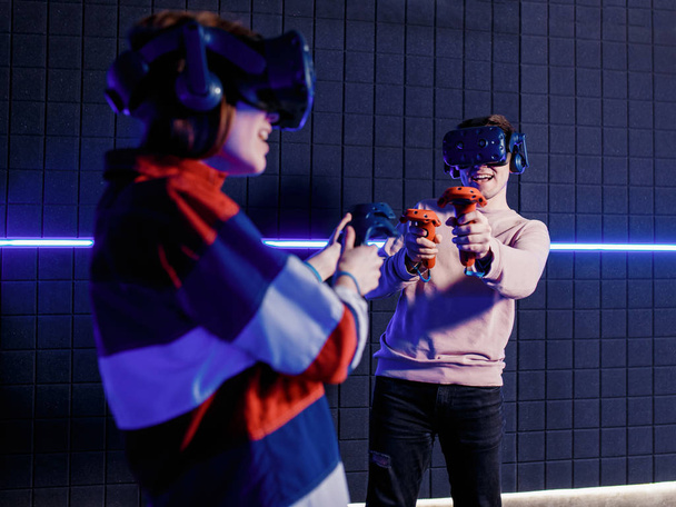young guy and girl in a virtual reality helmet playing video games in a club - Fotoğraf, Görsel