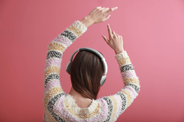 Young woman with headphones listening to music on color background - Photo, image