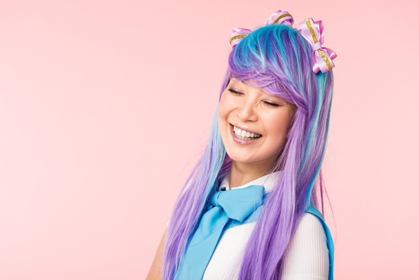 Menina de anime na peruca sorrindo com os olhos fechados isolados em rosa
 - Foto, Imagem