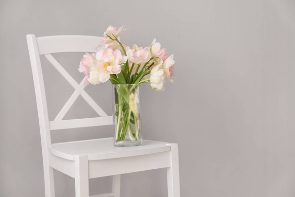 Bouquet of beautiful tulips on chair against grey background - Fotoğraf, Görsel