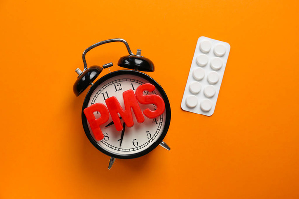 Klok, pillen en woord PMS op kleur achtergrond - Foto, afbeelding
