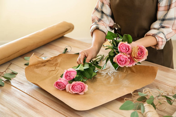 Флорист делает красивый букет за столом
 - Фото, изображение