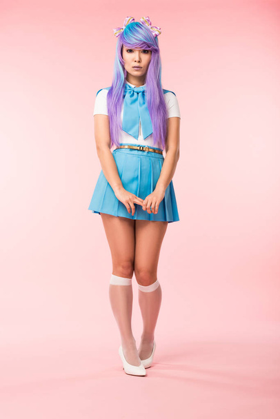 Full length view of sad asian anime girl in skirt standing on pink - Foto, Bild