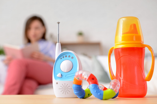 Modern baby monitor with bottle and toy on table in room - Foto, Imagen