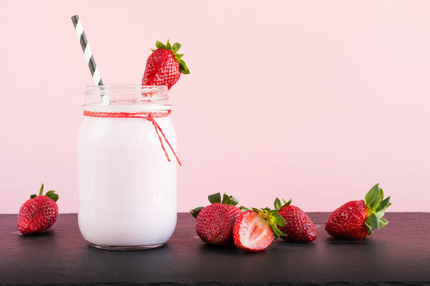 Strawberry milkshake with berry in mason jar on pink. Close up. Summer drink. - Photo, image