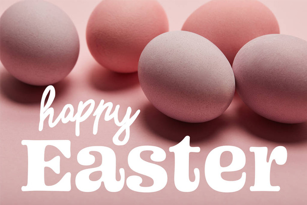 painted pink eggs on pink surface with white happy Easter lettering - Foto, afbeelding