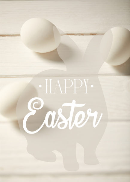 chicken eggs on white wooden table with happy Easter lettering and bunny illustration - Foto, Imagem