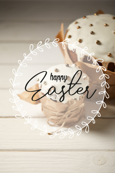 selectieve focus van de traditionele Pasen taarten in ambachtelijke papier op witte tafel met Happy Easter belettering  - Foto, afbeelding