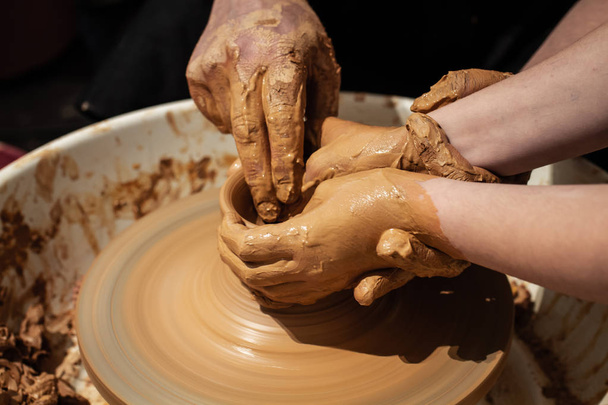 Expert potter teach a child to work on potter wheel - Photo, Image