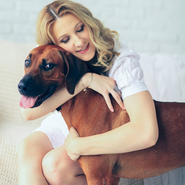 Pregnant woman and a dog sitting on the couch - Foto, imagen